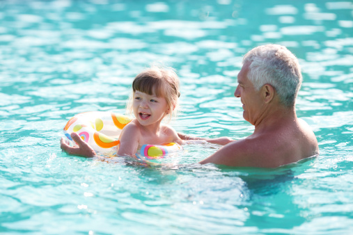 Grandfather and granddaughter swimming in the pool.