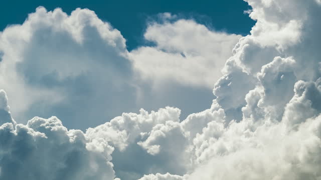 Time lapse of white fluffy cumulonimbus clouds forming before thunderstorm on summer blue sky. Moving and changing cloudscape weather