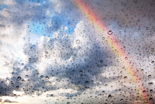 Texture of Rainbow, dramatic sky and water drops on the glass