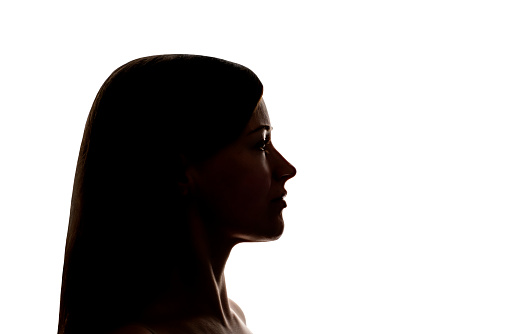 Dark silhouette of a young woman on a white background side view, the concept of anonymity.