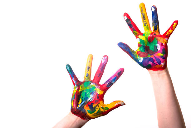 Child's hands covered in multicolored paint on a white back stock photo