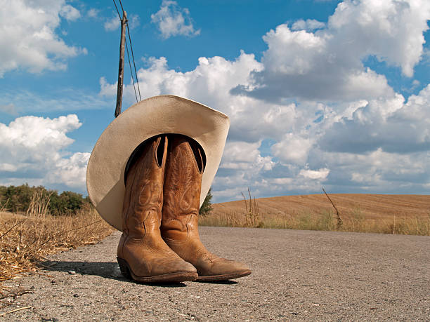 istock Cowboy boots and hat in a road 153524501