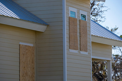 Plywood storm shutters for hurricane protection of house windows. Protective measures before natural disaster in Florida.