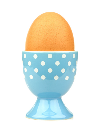 colorful and decorated blue and white egg cup with an egg on a white background
