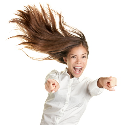 happy crazy excited woman screaming and pointing at camera with wild long hair in the wind. Beautiful ecstatic mixed race Caucasian Asian female model.