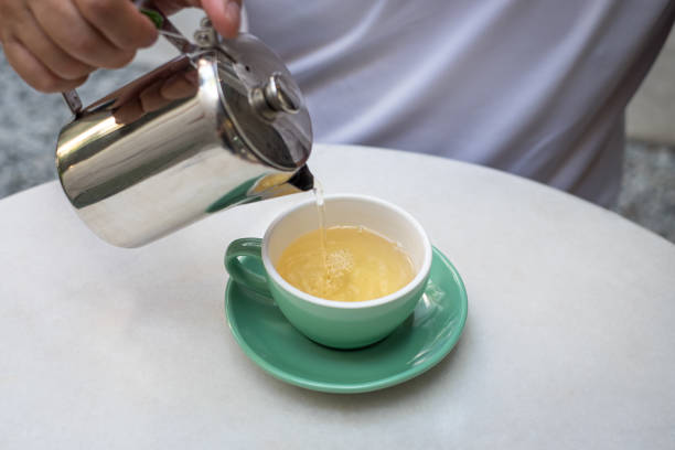 Pouring hot tea from pot to cup.