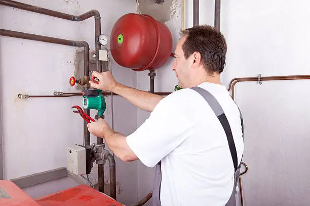 studio-shot of a heating engineer repairing and maintaining the heating system of a single-family house