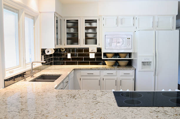 A modern kitchen with white cabinets and countertop stock photo