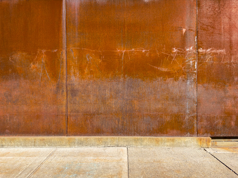 Rusty metal wall and empty sidewalk