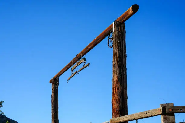 Angled view of old West wooden gate with rusted wagon wheels at horse ranch in the mountains