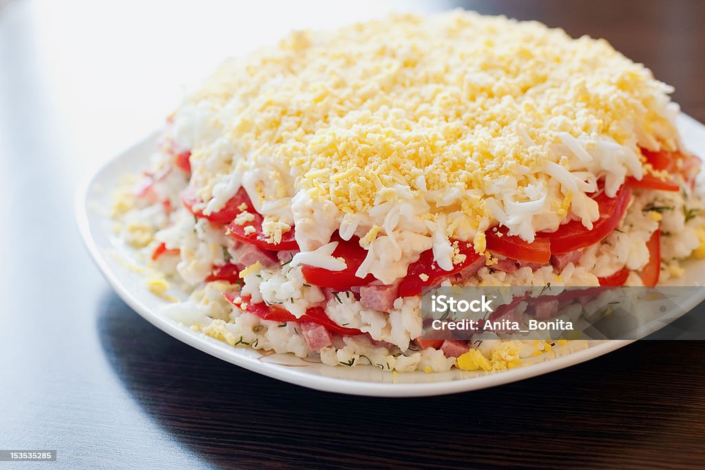 Salad With Rice, Cheese And Sausage close-up salad made with layers of rice, tomatoes, sausage, cheese and eggs Appetizer Stock Photo