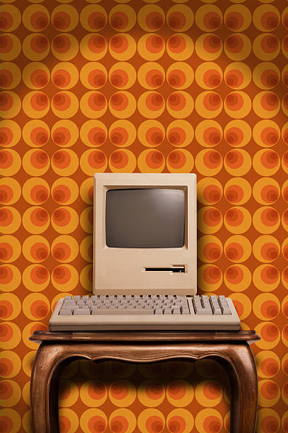 Old desktop computer on wooden table and seventies wallpaper An old classic computer from the eighties against a colourful wallpaper from the seventies, with plenty of copy space for editing. crt computer screen stock pictures, royalty-free photos & images