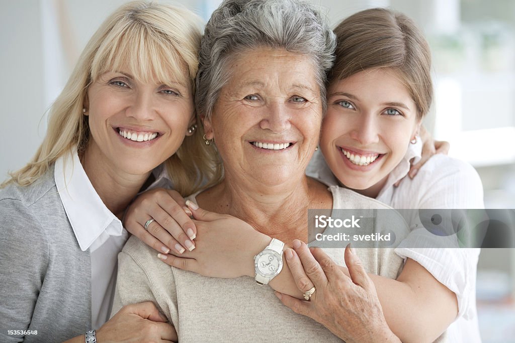 Three female generations. Three generations of woman hugging and looking at camera. Multi-Generation Family Stock Photo