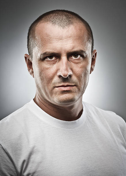 A portrait of a man with a stern face Fine art portrait of a menacing man, studio close up rough face stock pictures, royalty-free photos & images