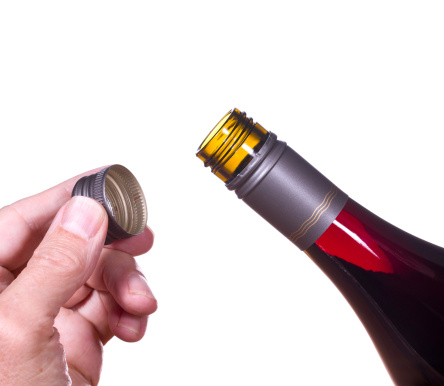Red or rose wine in screw top wine bottle  isolated against white with hand holding the cap by the neck of bottle