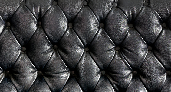 Closeup texture of vintage black leather sofa for background.