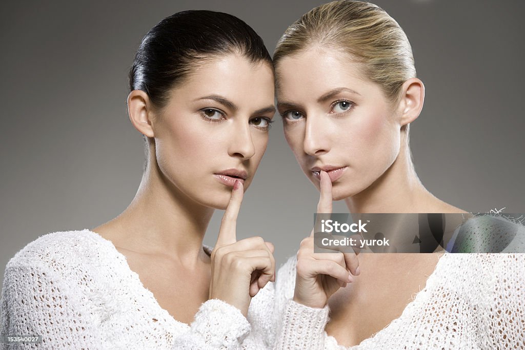 women's secrets two young caucasian women gesturing shh - keep it secret Adult Stock Photo