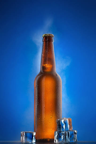 istock Cold beer bottle with drops, frost and vapour on blue 153541929