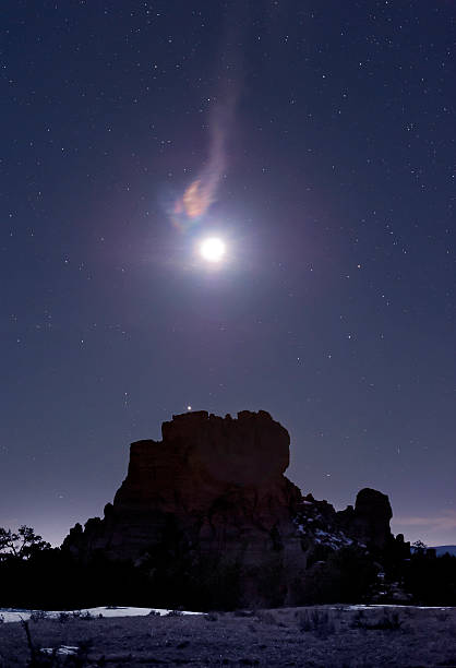 Flaming moon over rock monument at night stock photo