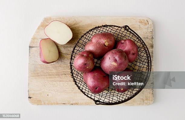 Rojo Papas En Cesta De Alambre En La Tabla De Cortar Foto de stock y más banco de imágenes de Patata roja