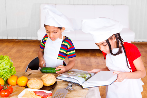 Kids reading cook book and making salad