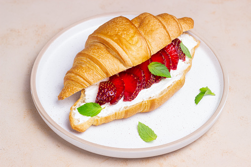 Croissant with strawberries, white cheese and mint. Breakfast. Vegetarian food