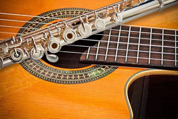 A 14k rose gold flute place on a cutaway classical guitar.
