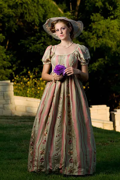 A young redheaded woman holds a bouqet of flowers while looking at the camera