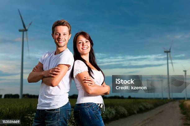 Potente Pareja En Frente Del Molino De Viento Foto de stock y más banco de imágenes de Adulto - Adulto, Adulto joven, Aerogenerador