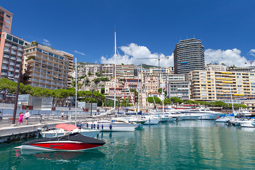 Monte Carlo, Monaco - August 15, 2018: Port Hercule view on a sunny summer day. Yachts and pleasure boats are moored in marina, tourists walk the street