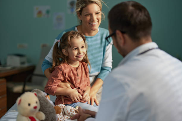 Smiling girl having an appointment with her mother at pediatricians'. Smiling girl having a medical appointment at her doctor's office with a support of her single mother. one parent stock pictures, royalty-free photos & images