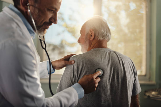 Let me take a listen to your lungs! Mid adult male doctor listening to senior man's lungs during an appointment in the office. bronchitis stock pictures, royalty-free photos & images