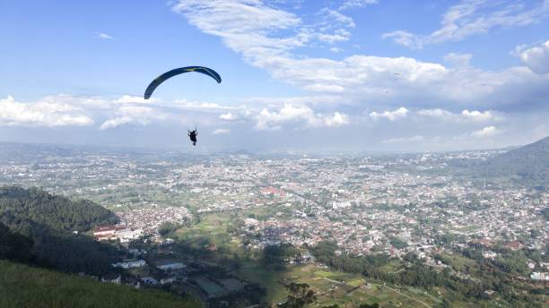 istock Paraglider flying high above village view and blue sky background 1535583244