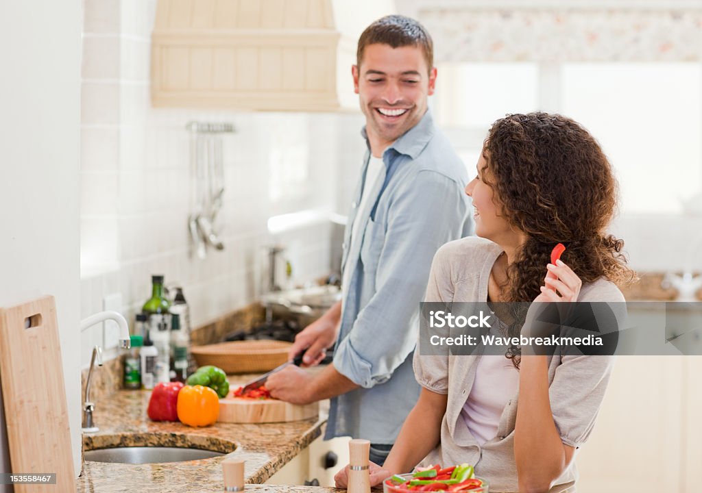 Beautiful woman looking at her husband who is cooking Beautiful woman looking at her husband who is cooking at home Couple - Relationship Stock Photo