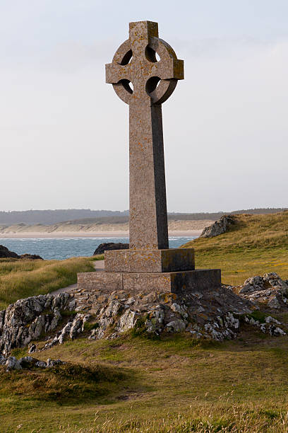 старый серый крест на фоне неба и моря. - wales stone cross religion стоковые фото и изображения