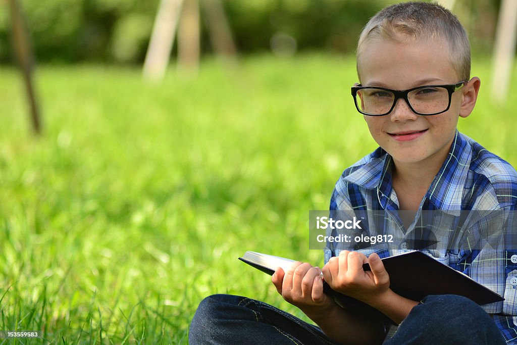 boy with a book in the park Young boy reading book at the park Book Stock Photo