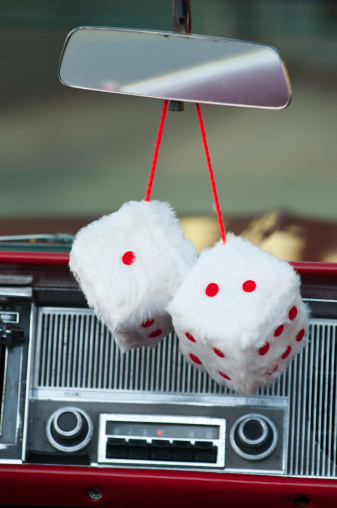 White fuzzy dice hanging from rear view mirror in vintage vehicle