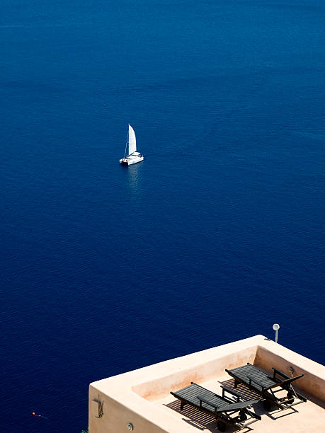 istock Blue sea, a white catamaran and two beach chairs 153559828