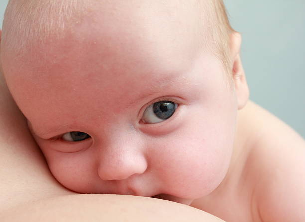 newborn looking from the mother's shoulder stock photo