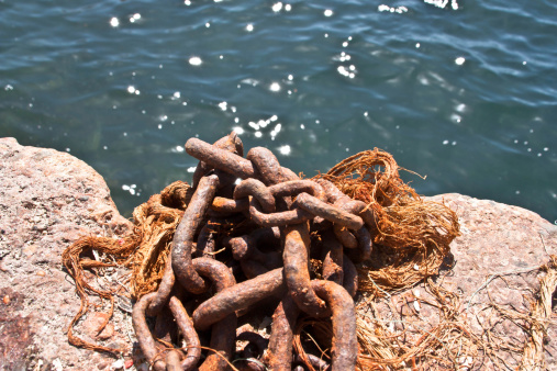 Wide link chain, designed for mooring boats,on rock, and background sea.