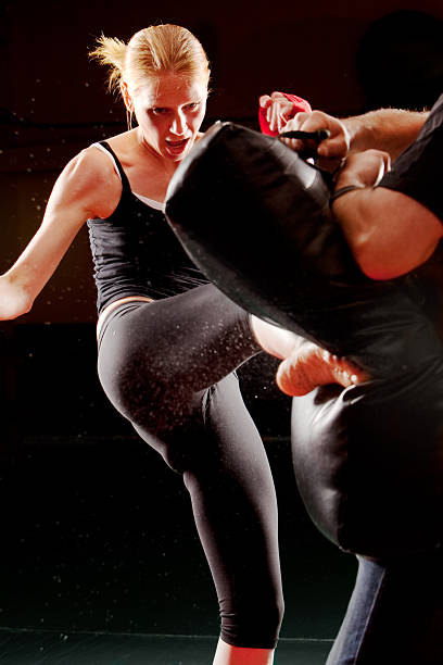 istock Female martial arts student kicks practice bag, vertical composition. 153560736