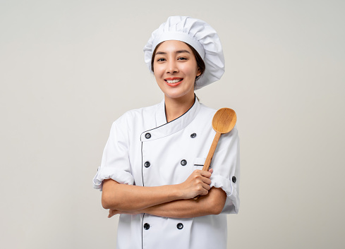 Young beautiful asian woman chef in uniform holding ladle utensils cooking in the kitchen various gesture delicious dish menu good taste on isolated. Cooking woman chef people in kitchen restaurant