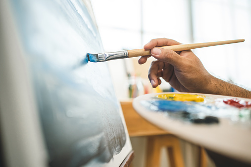Artista asiático trabajando en pintura con pincel y variante de color acrílico. Hombre artista pintor sobre lienzo en estudio creativo como concepto de arte photo