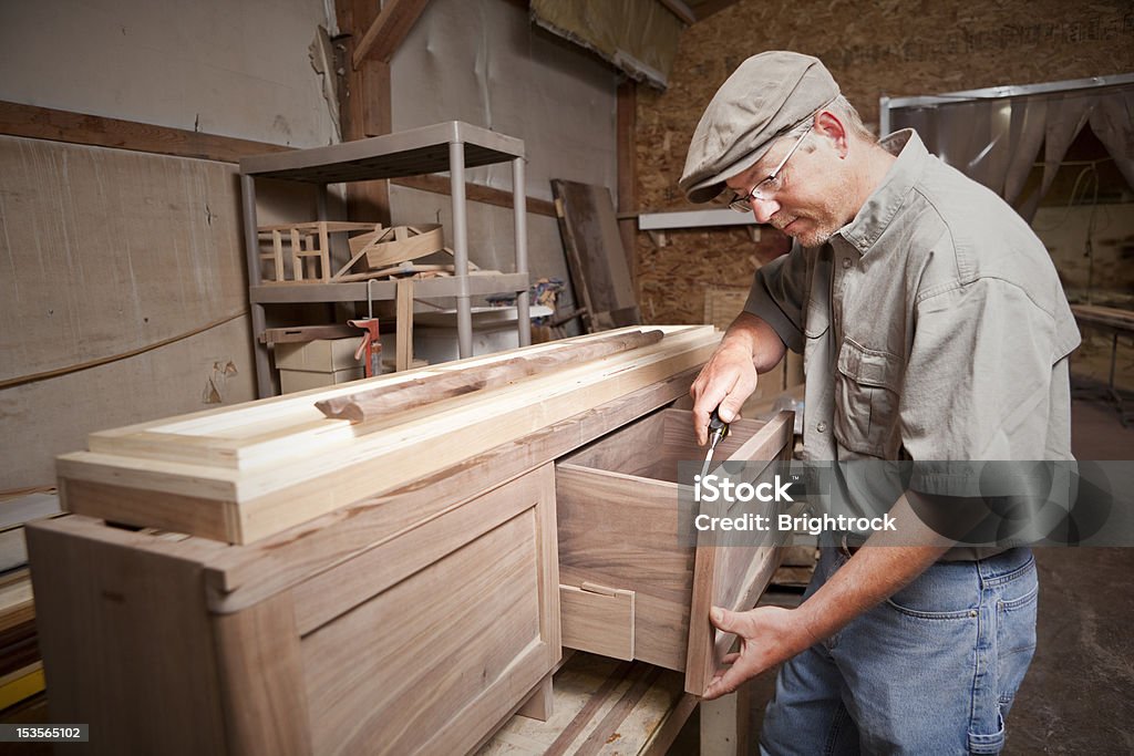 Carpenter uses chisel (tool) on cabinet drawer A carpenter using a chisel on a cabinet drawer in a workshop. Customized Stock Photo