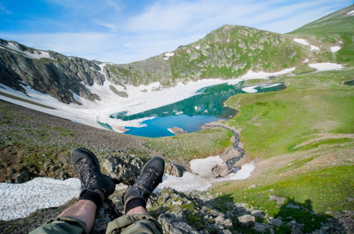 Personal perspective of woman  relaxing on top of Rila Mountain . Feet view . Travel vacations concept