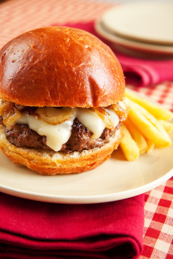 Thick rare cheeseburger with swiss cheese and caramelized onions served with french fries