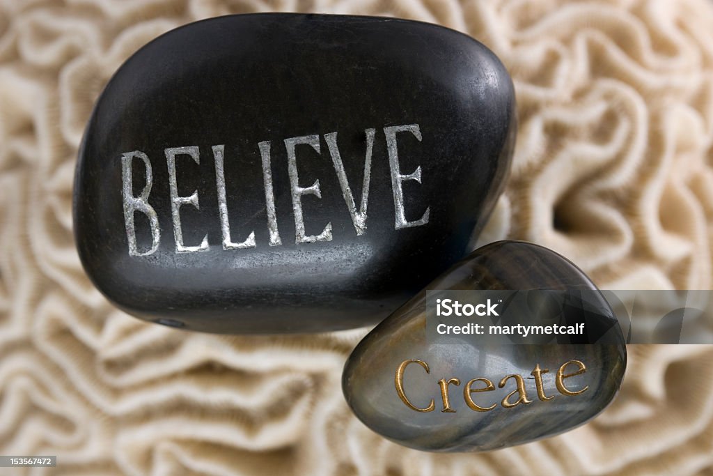 Believe and Creat The words Believe and create, on stones with soft Brain Coral background. Black Color Stock Photo