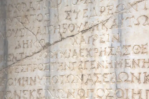 Photo of So-called Syedra inscription (ancient law at Ancient Greek). The law edited by Roman emperor Septimius Severus, III cent AD. Cracked marble block. Retro background. Alanya, Turkey, Augus 07, 2022