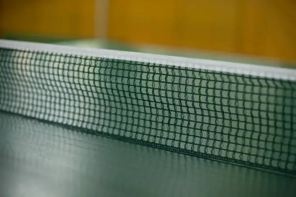 Photo of Table tennis net. Tennis table. Mesh is stretched across table.