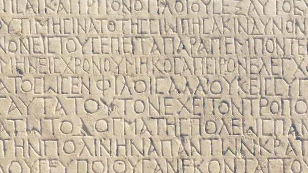 Photo of Historical inscription (the text of law at Ancient Greek language). Carving on marble block at the archaeological site of Ephesus. Retro background. Selcuk, Turkey (Turkiye). Oct. 05, 2022